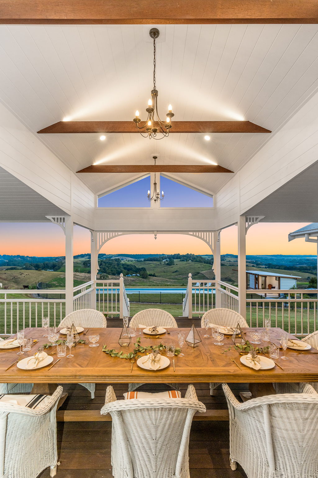 Aurora House in the Byron Bay hinterland has a dining table overlooking a magnificent rural view at sunset.