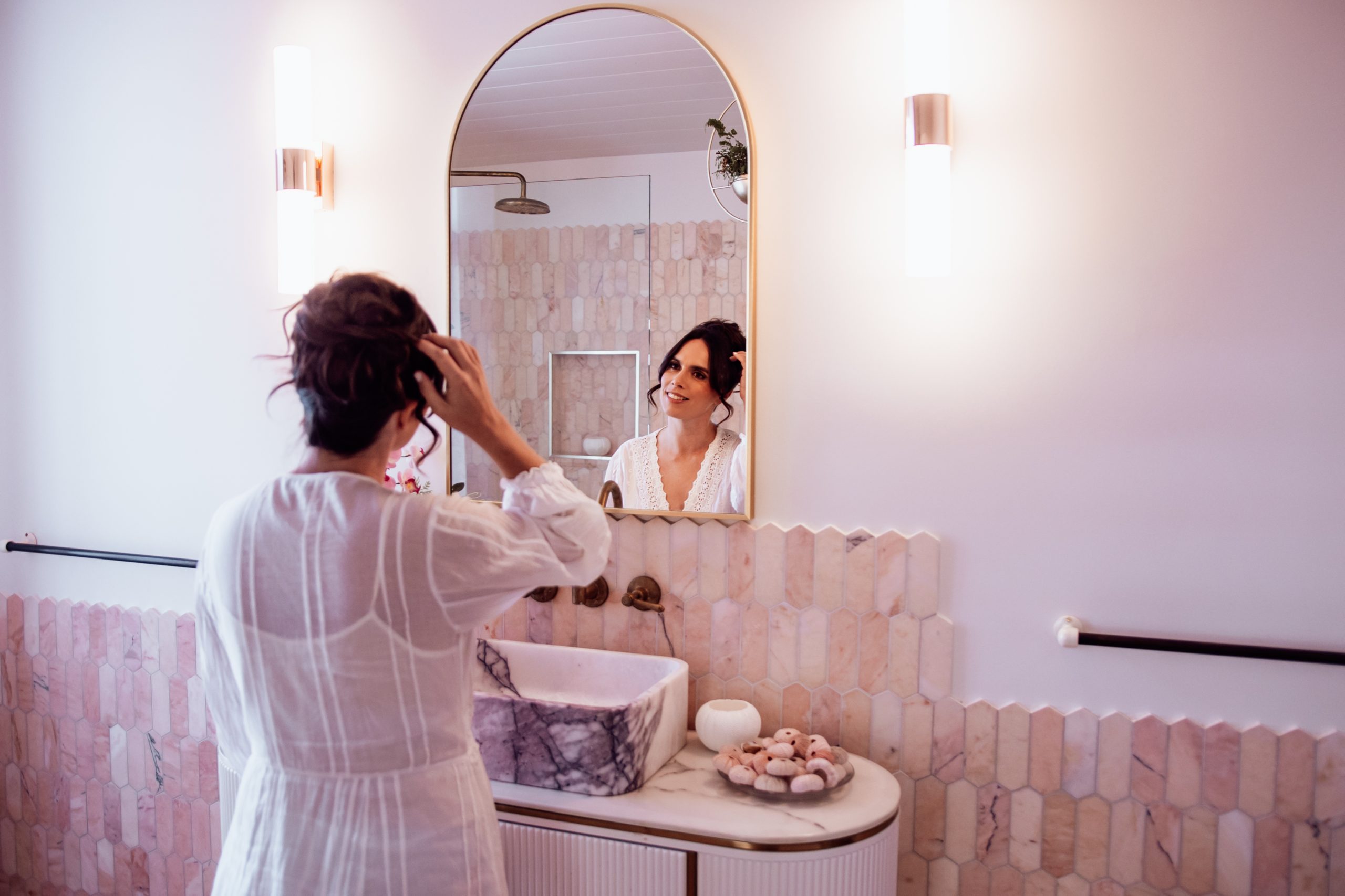 Bride getting ready at her Byron Bay wedding venue and accommodation looking in mirror doing her hair
