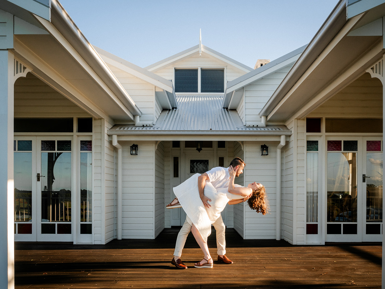 Couple do a wedding dip on the front deck of wedding venue Aurora House, Byron Bay